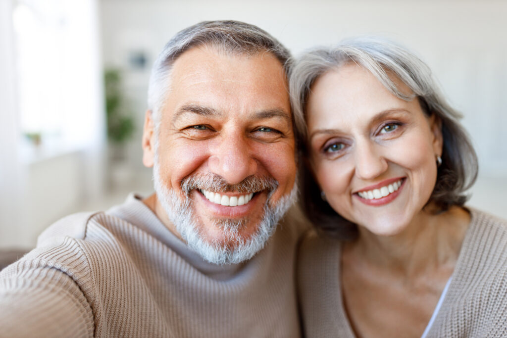 Smiling older couple representing patients considering full or partial dentures.